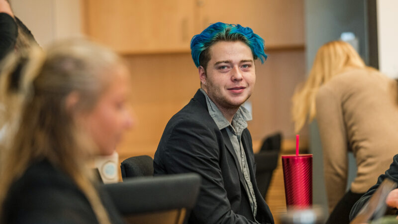 student with colorful hair looks at camera