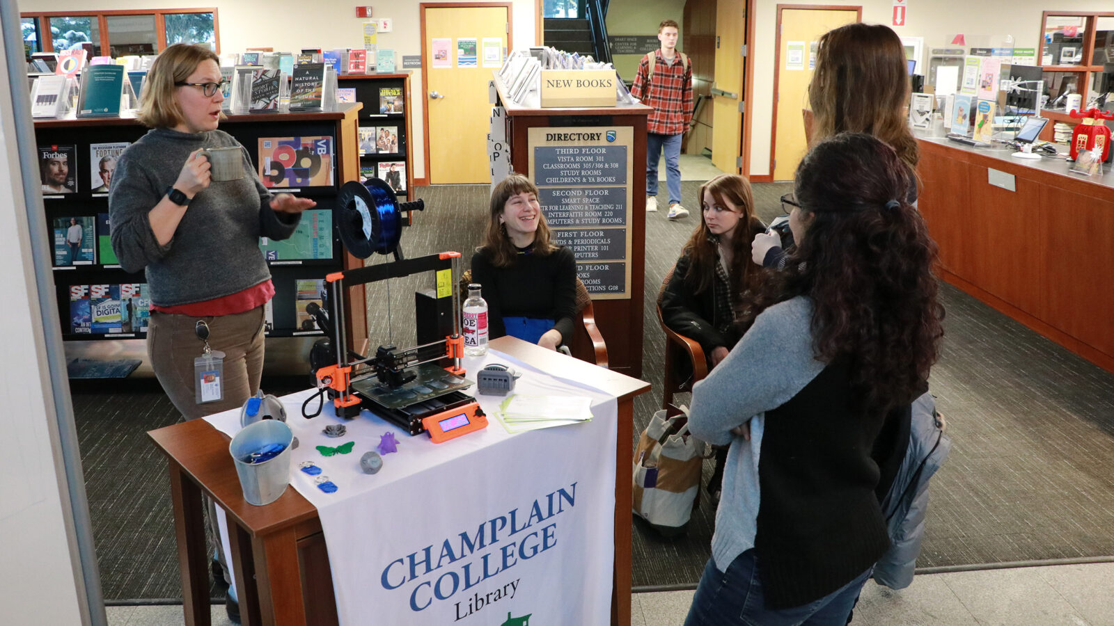 3D Printer exhibition on the first floor of the library. Several students and employees talk while watching the 3D printer demo.