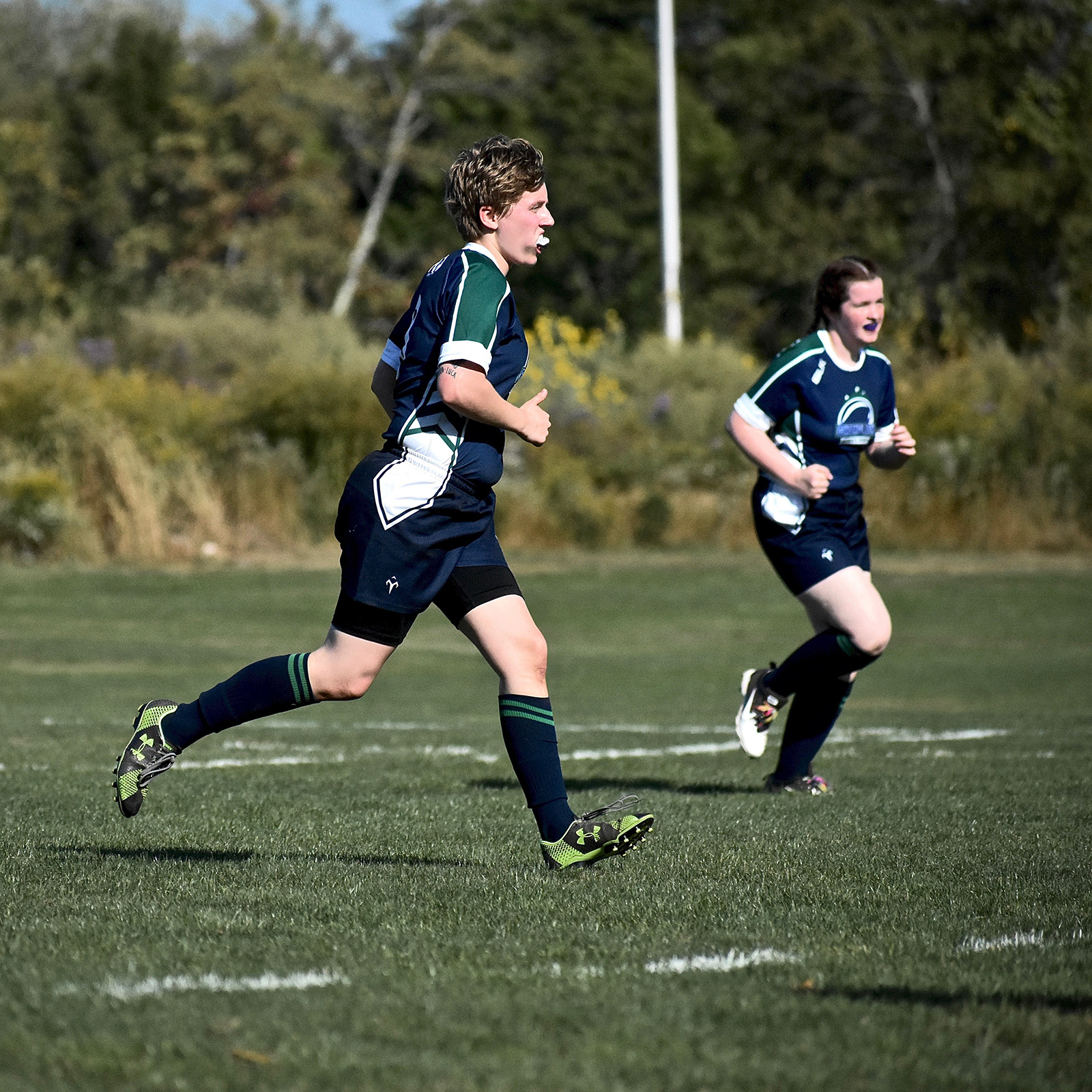 two rugby players running across grass