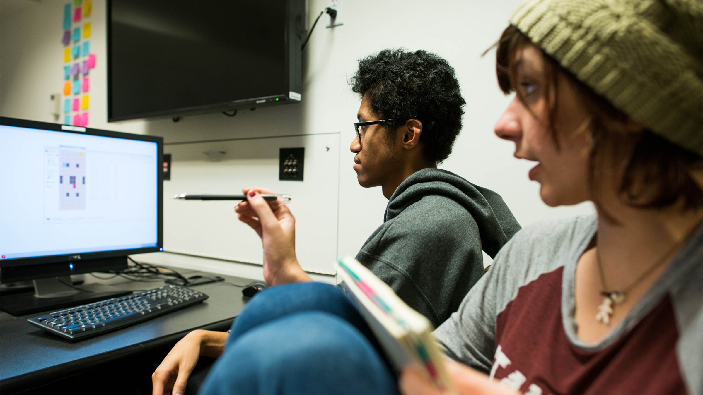 two students collaborating on a game design project in front of a computer screen