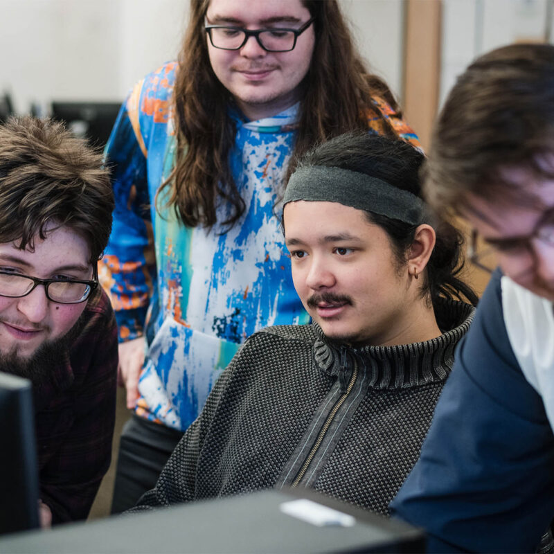 A group of Game Business students collaborating around a computer