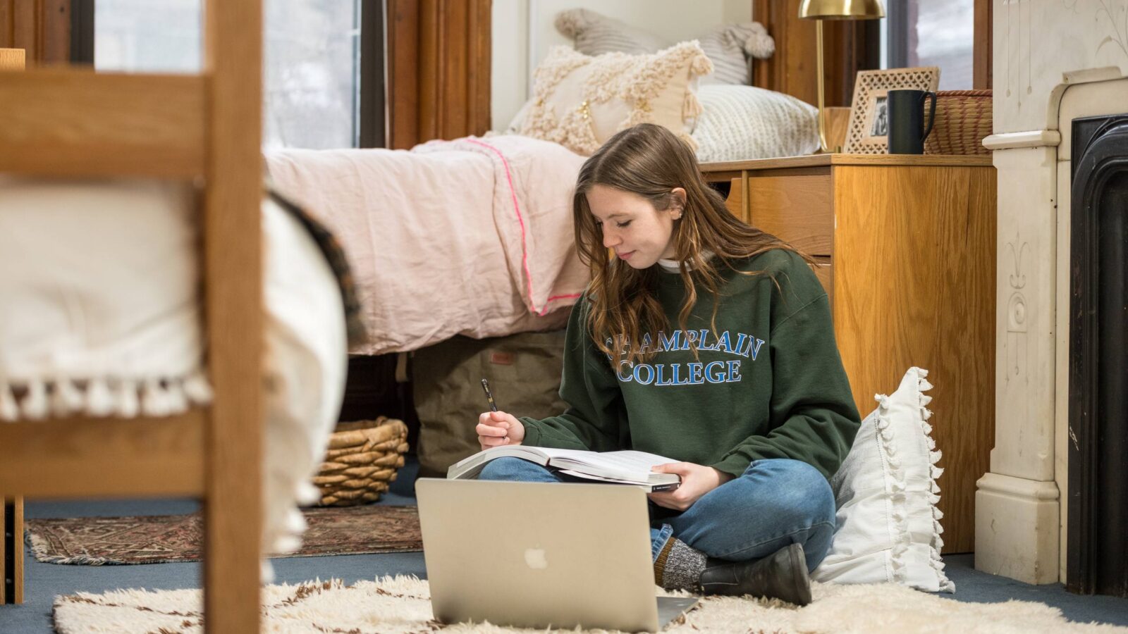 Student sitting on the dorm floor working in a notebook and laptop