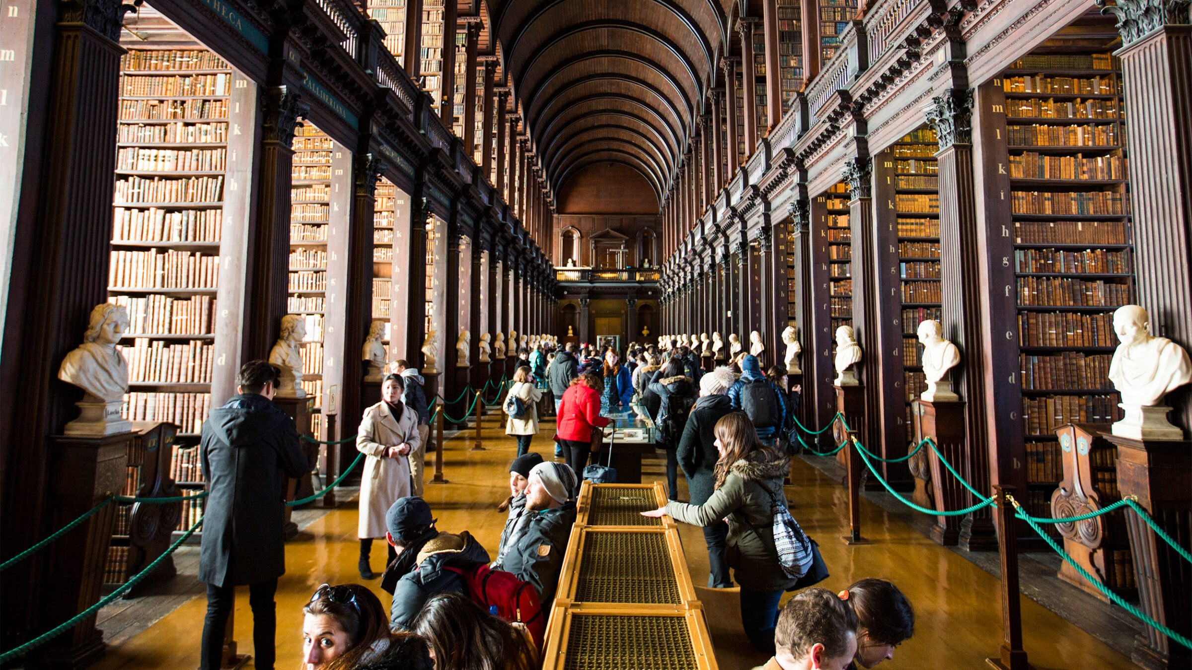 a large group of students and people lining the hall of a large, classic library in dublin