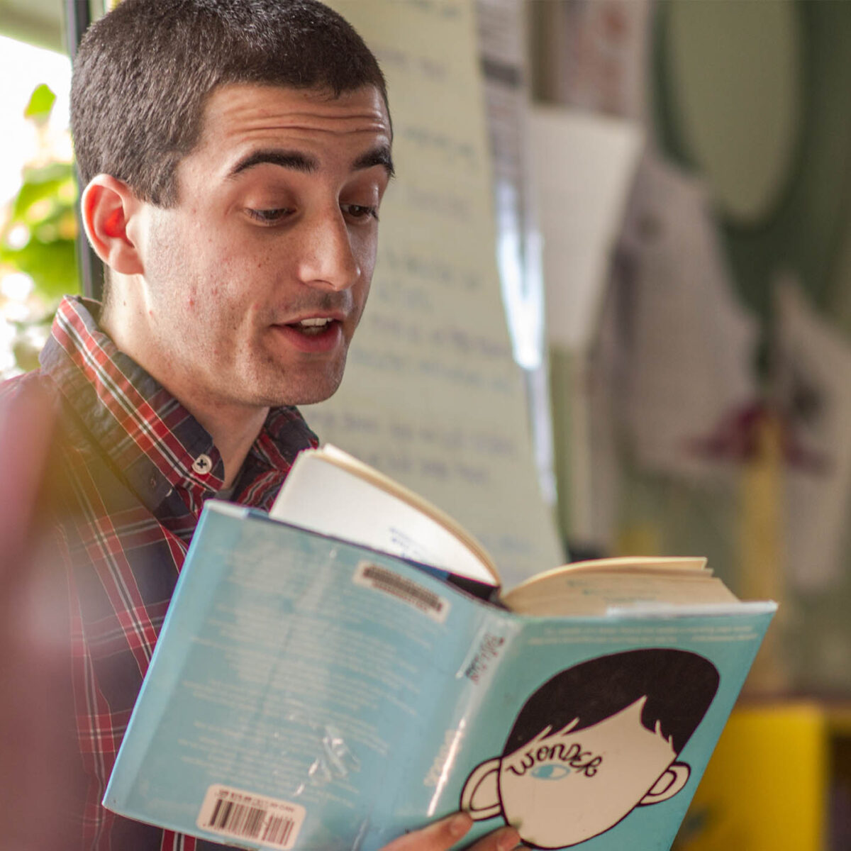 an education student reading a children's book in a classroom; student teaching