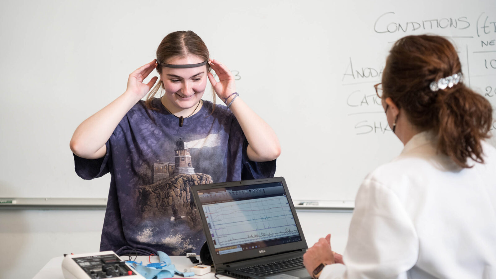psychology student and professor using brain scanner and getting data on a laptop