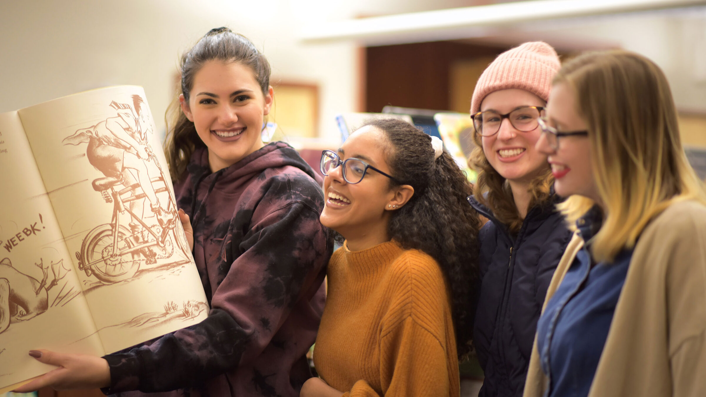 Four students look at an illustration book in the library