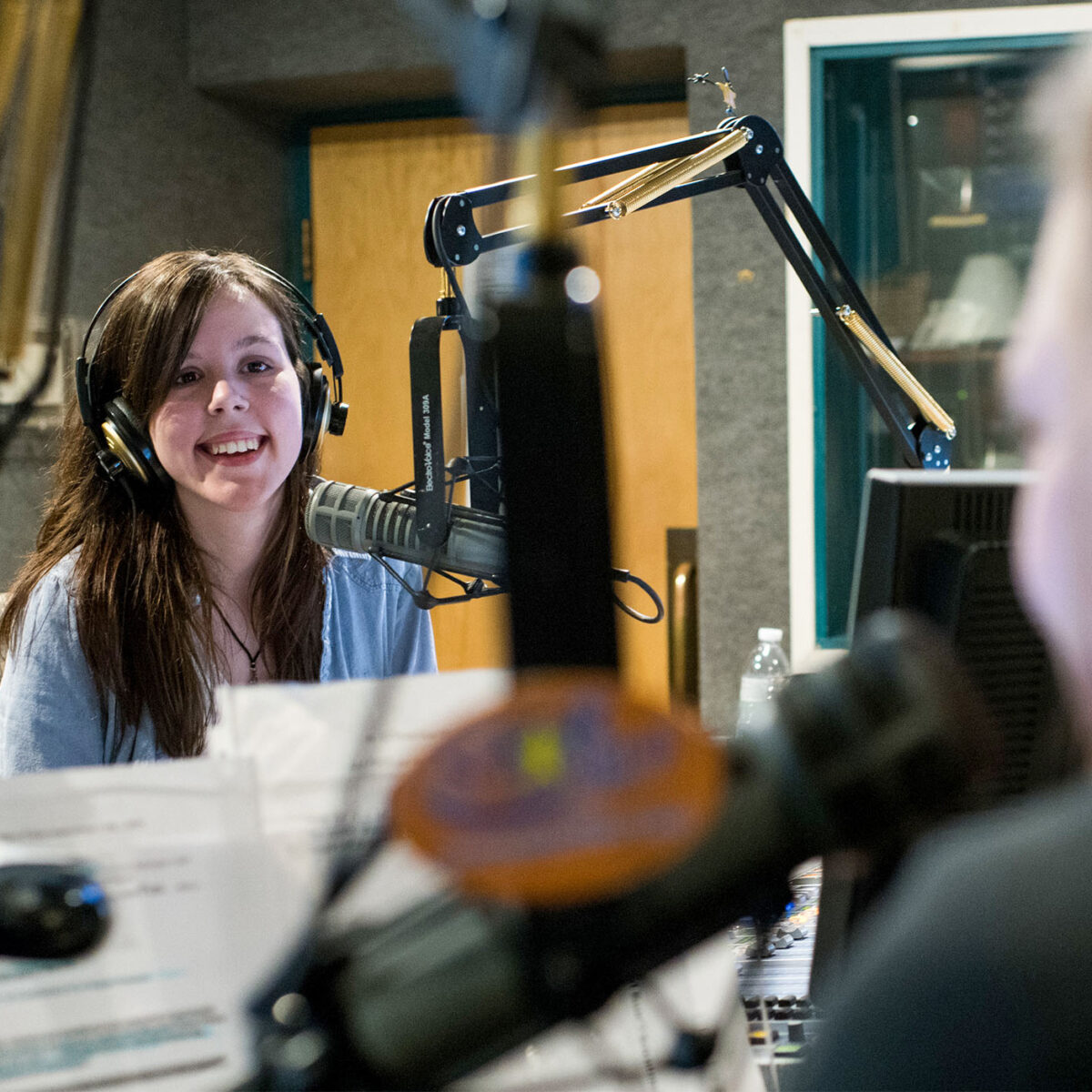 broadcast media student recording audio from a professional sound booth