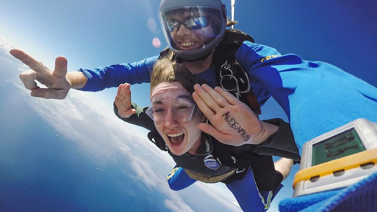 tandem sky diving; audeamus written in ink on one person's hand