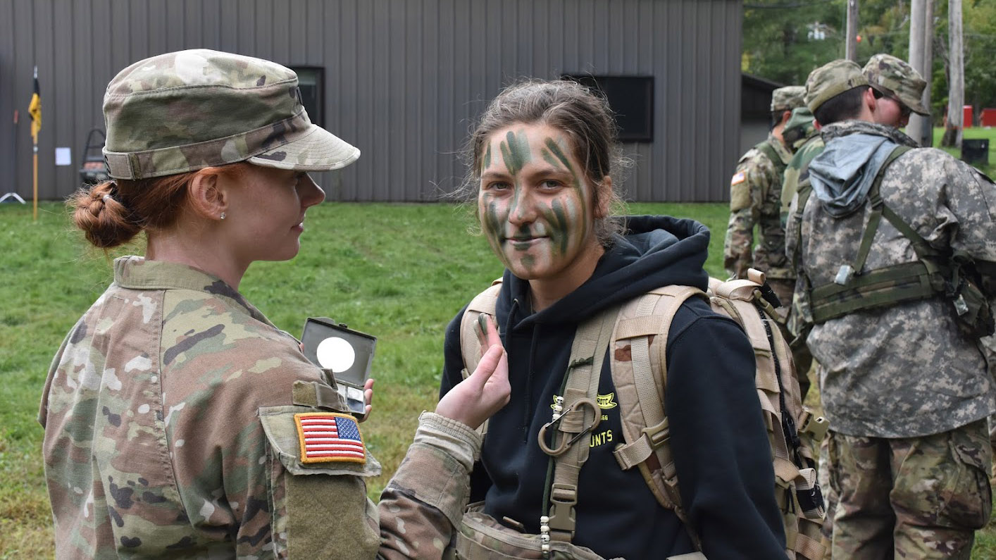 two cadets apply face paint getting ready for training