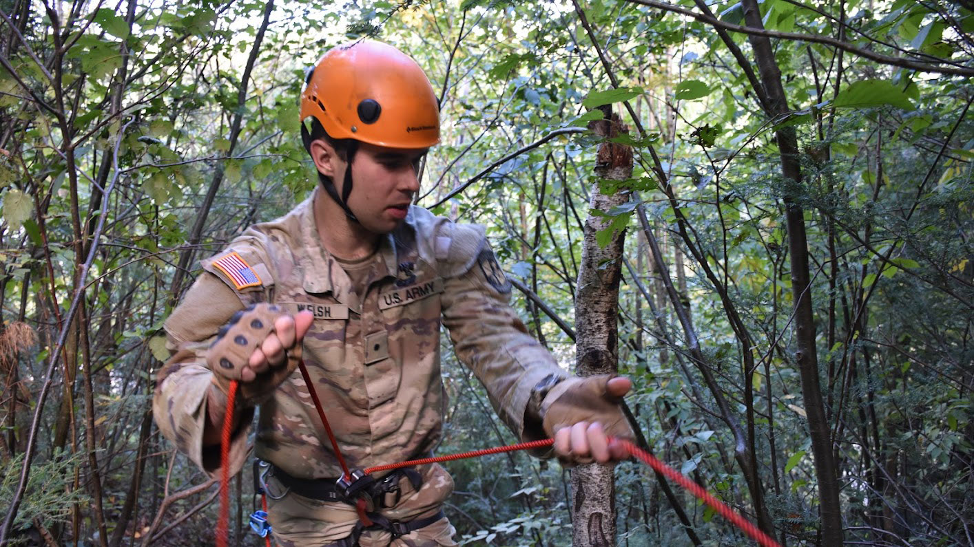 cadet in fatigues has rope and helmet ready to rappel in forest