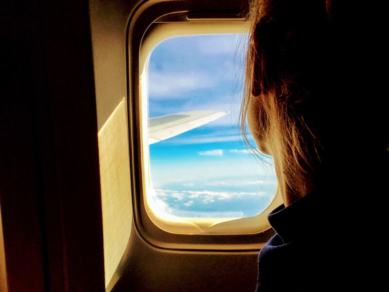 young woman looking out the window of an airplane