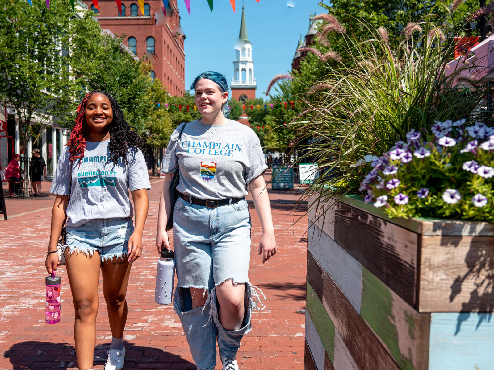 two students walking down church street wearing Champlain college merchandise