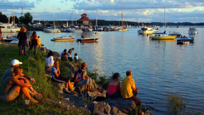 Pedestrians sitting by Lake Champlain watching the sunset