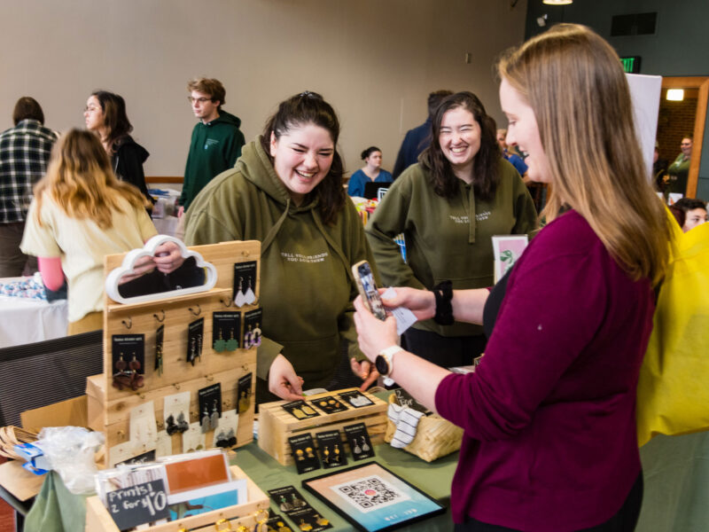 Two alumni sell earrings at the Champlain Weekend Market