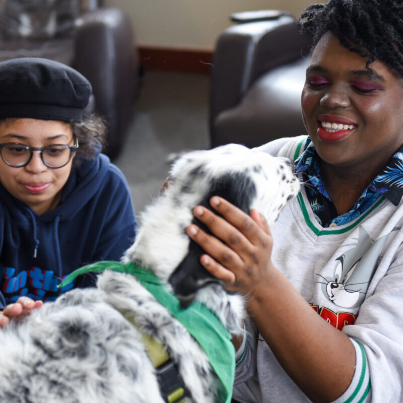 two students enjoys times with a therapy dog