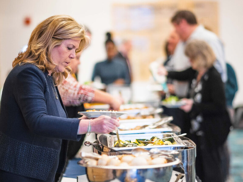 a staff member helping herself to the lunch bar at a catered event