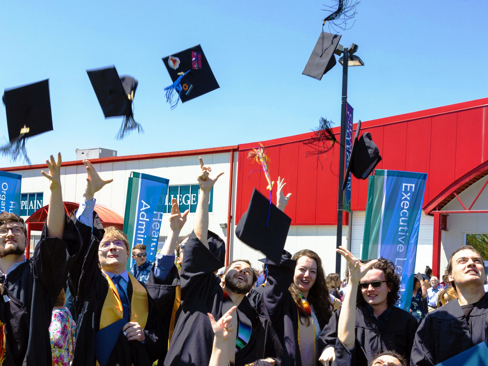 Champlain graduates toss their caps into the air in celebration.