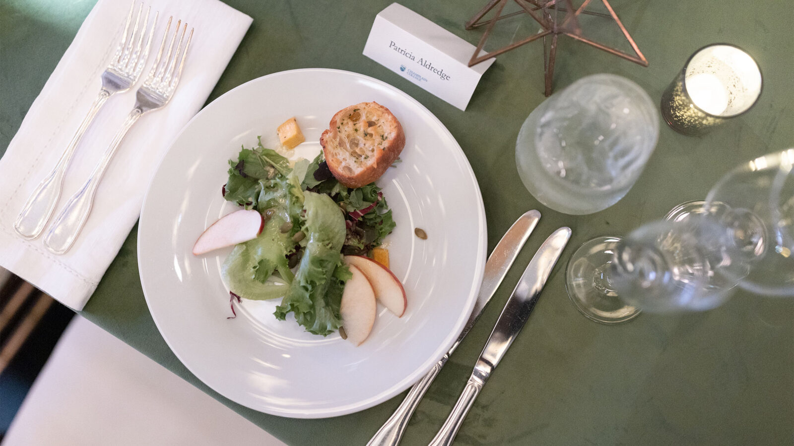 a fancy dinner plate catered with salad and a name card