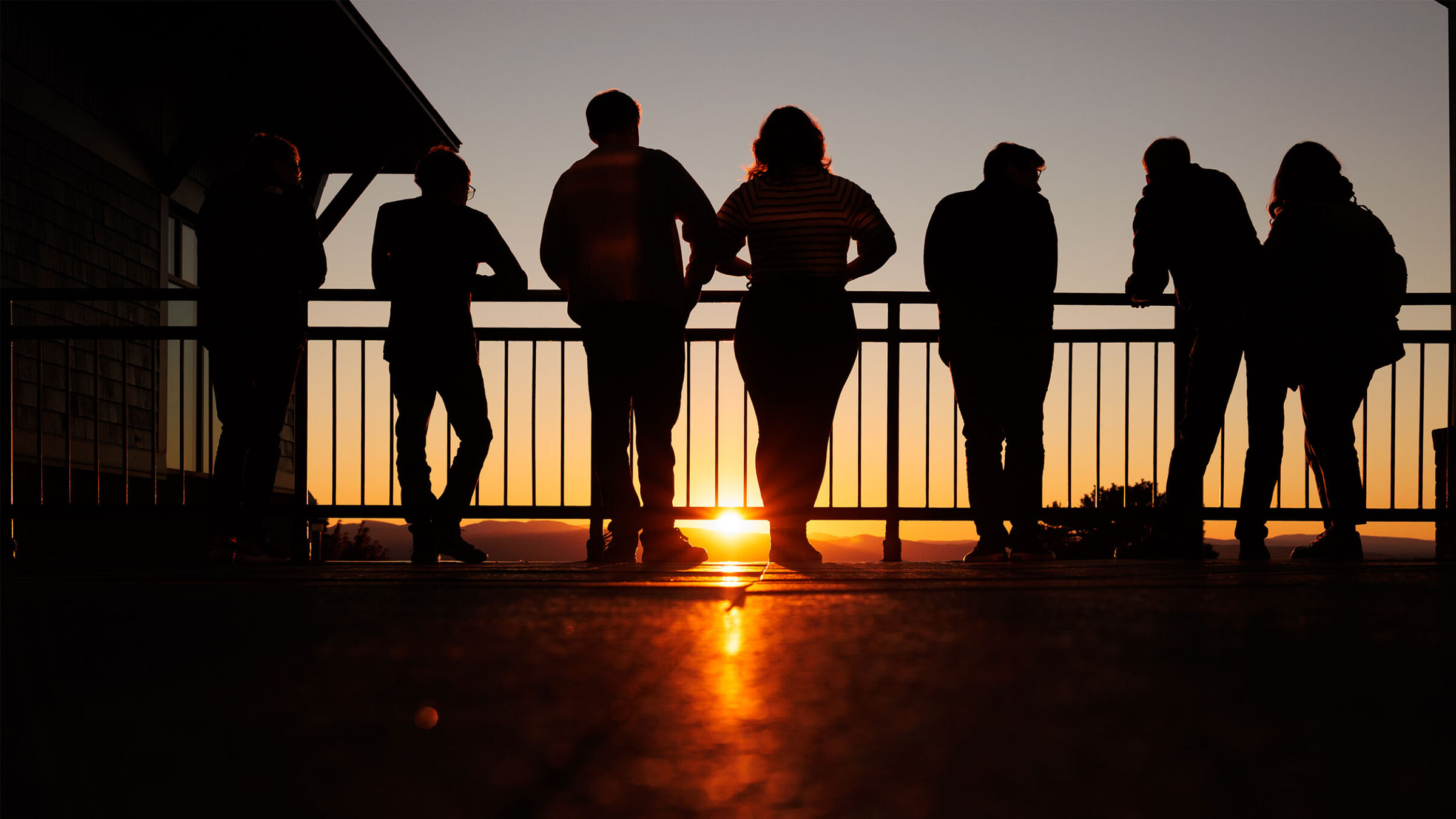 a group of students watching the sunset from atop a champlain college balcony