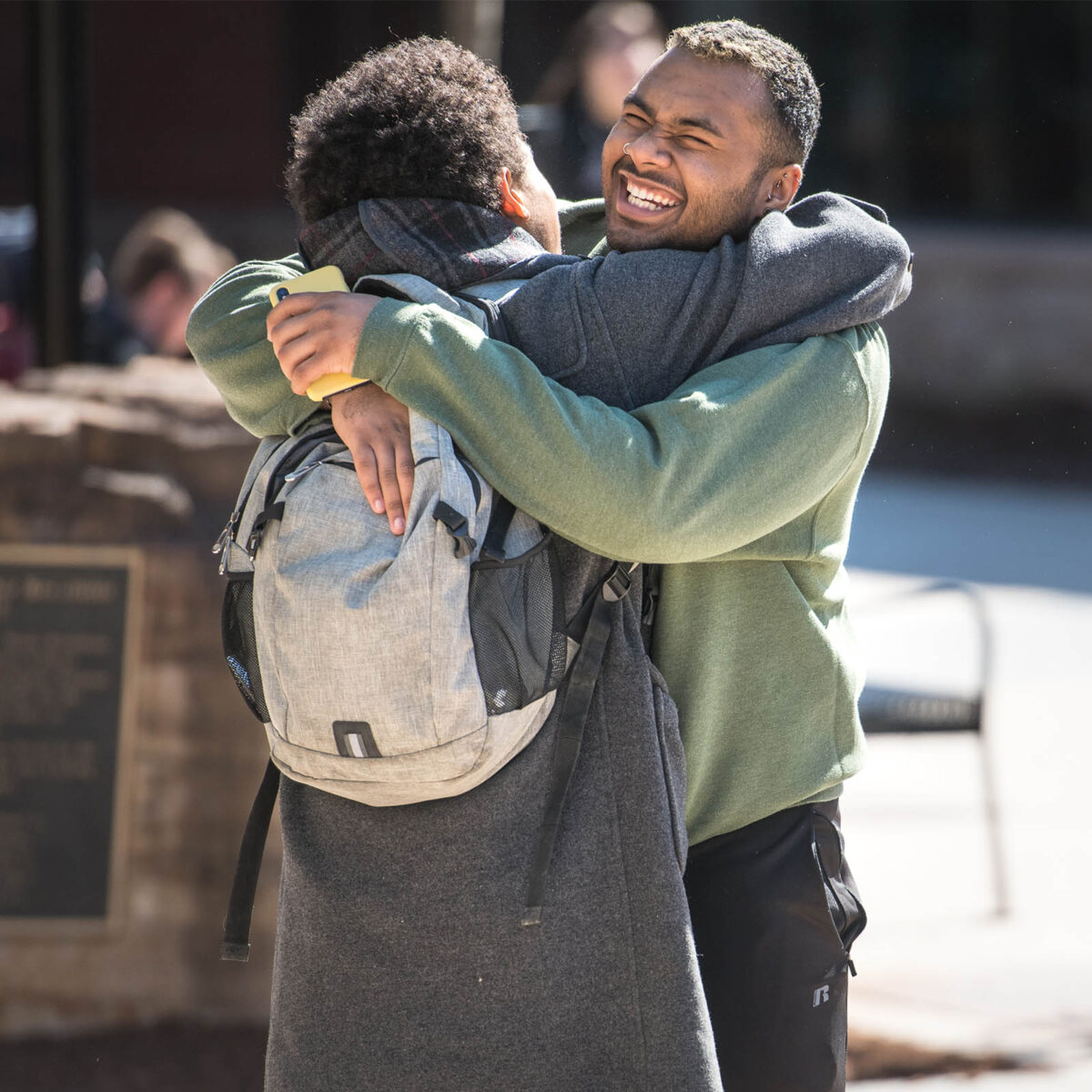 two students hug as a greeting, smiling