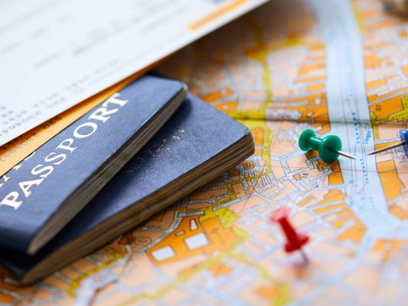 pins on a map with a passport and plane tickets