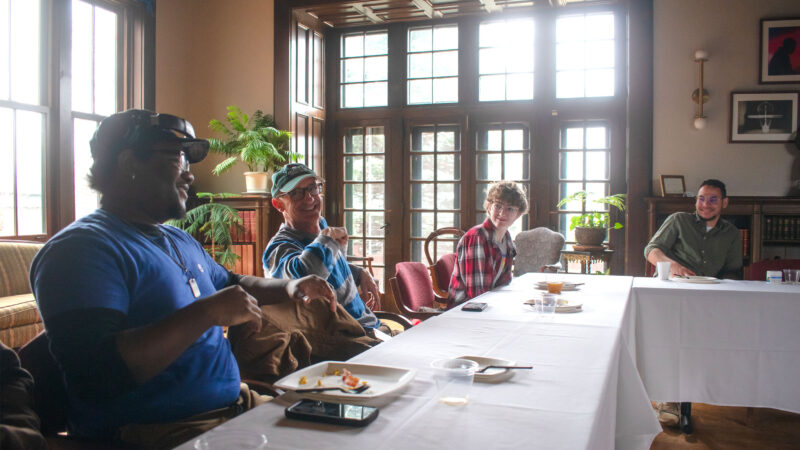 four students sit at a table in the morgan room. light shines in through the window and everyone is smiling and laughing with empty brunch plates in front of them.