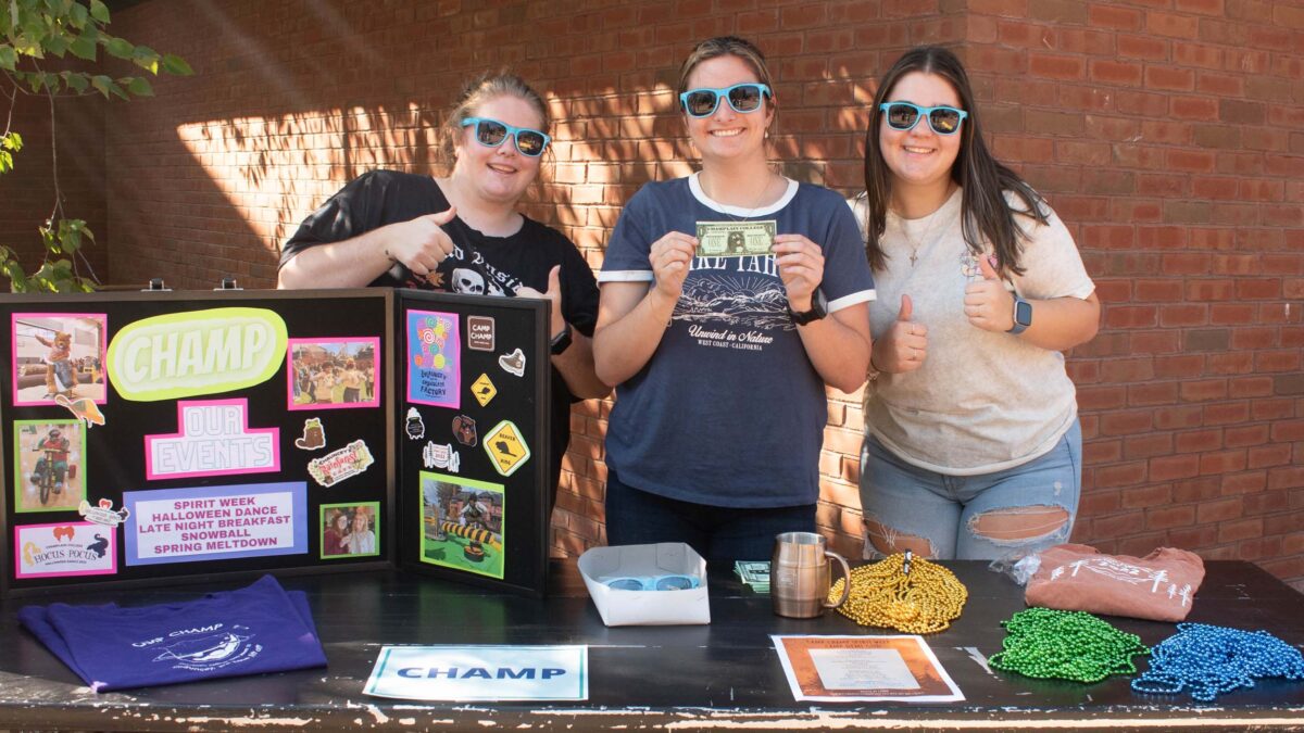 CHAMP students with a poster describing their club holding chauncey bucks during the activity fair