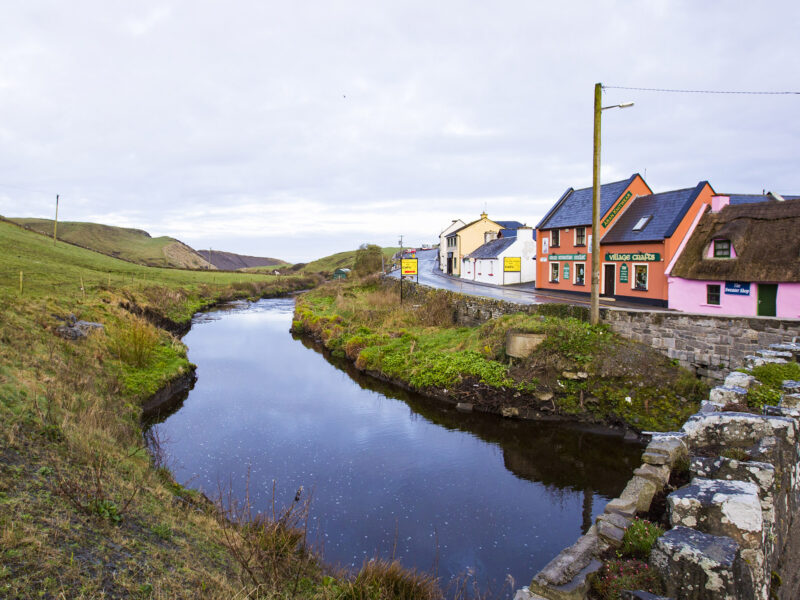 colorful house in Ireland near a stream, field and stone bridge