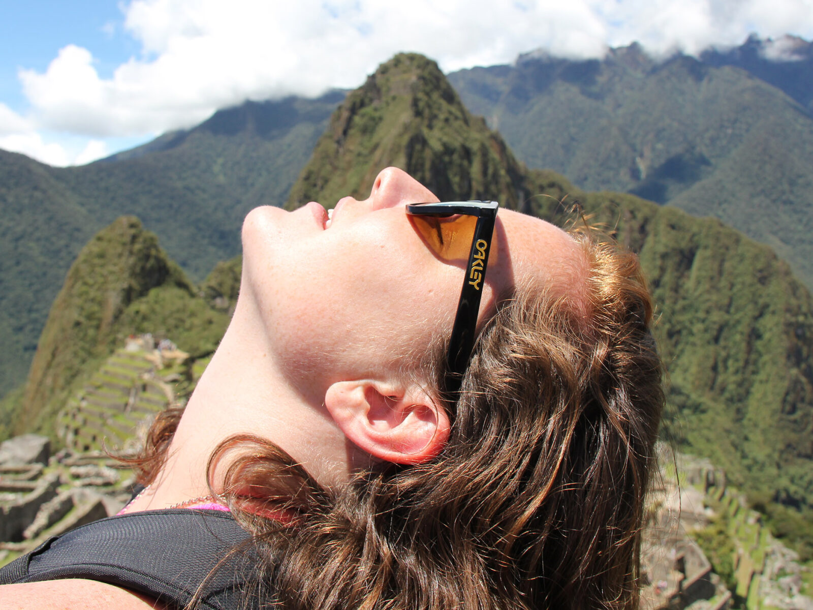 Sarah Ramsey '12 holds turns face up toward the sun, mountains behind her