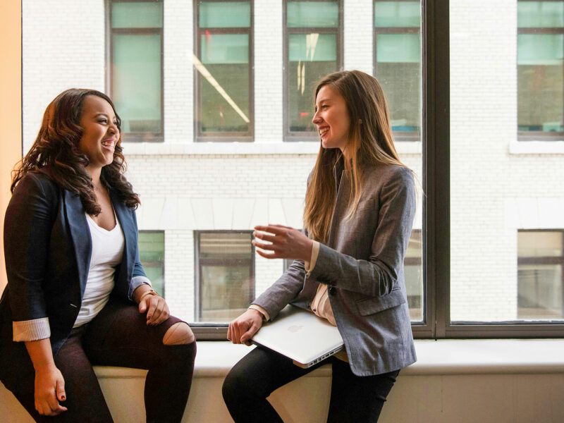 women colleagues chat in the hall near a window