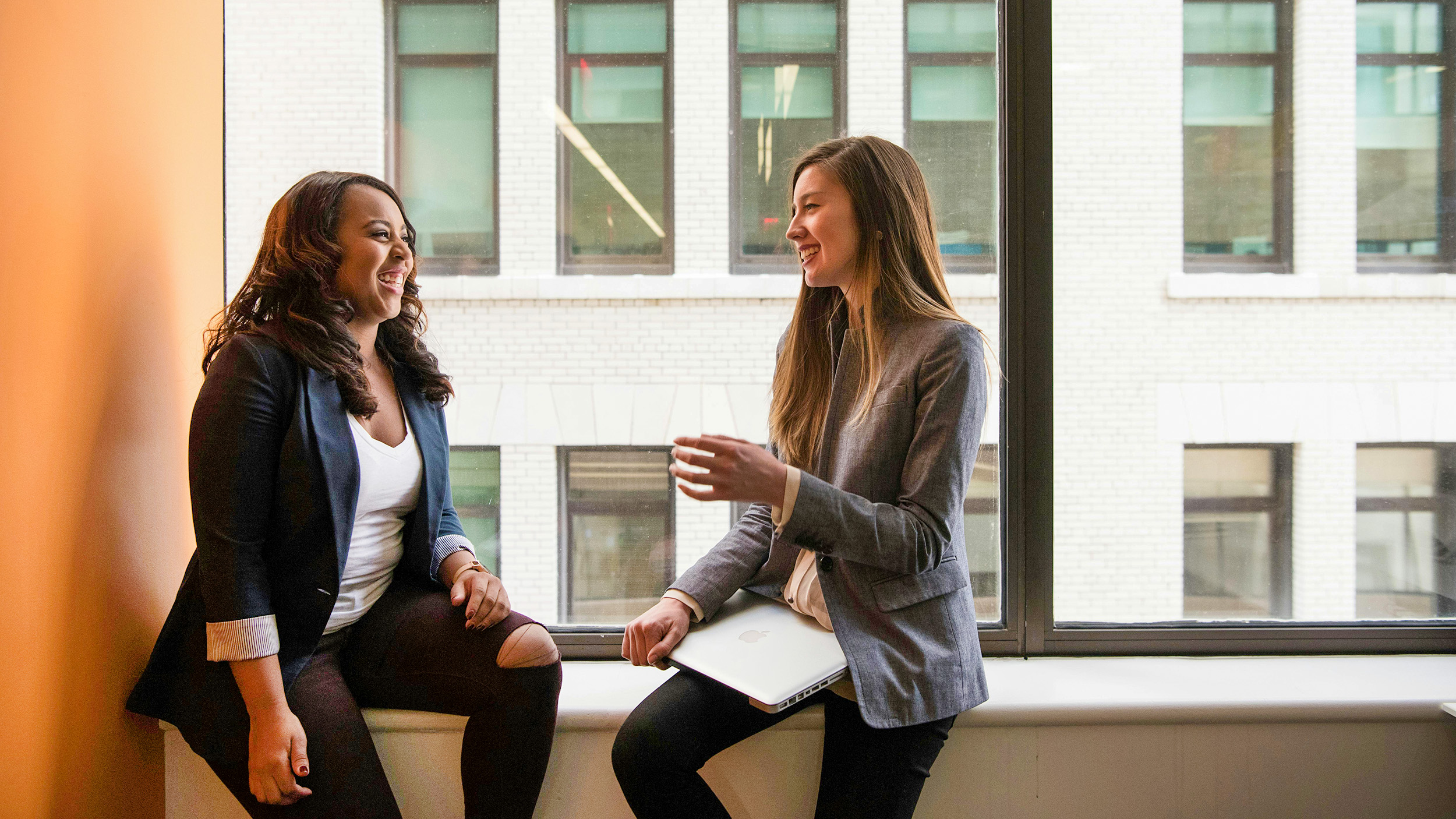 women colleagues chat in the hall near a window