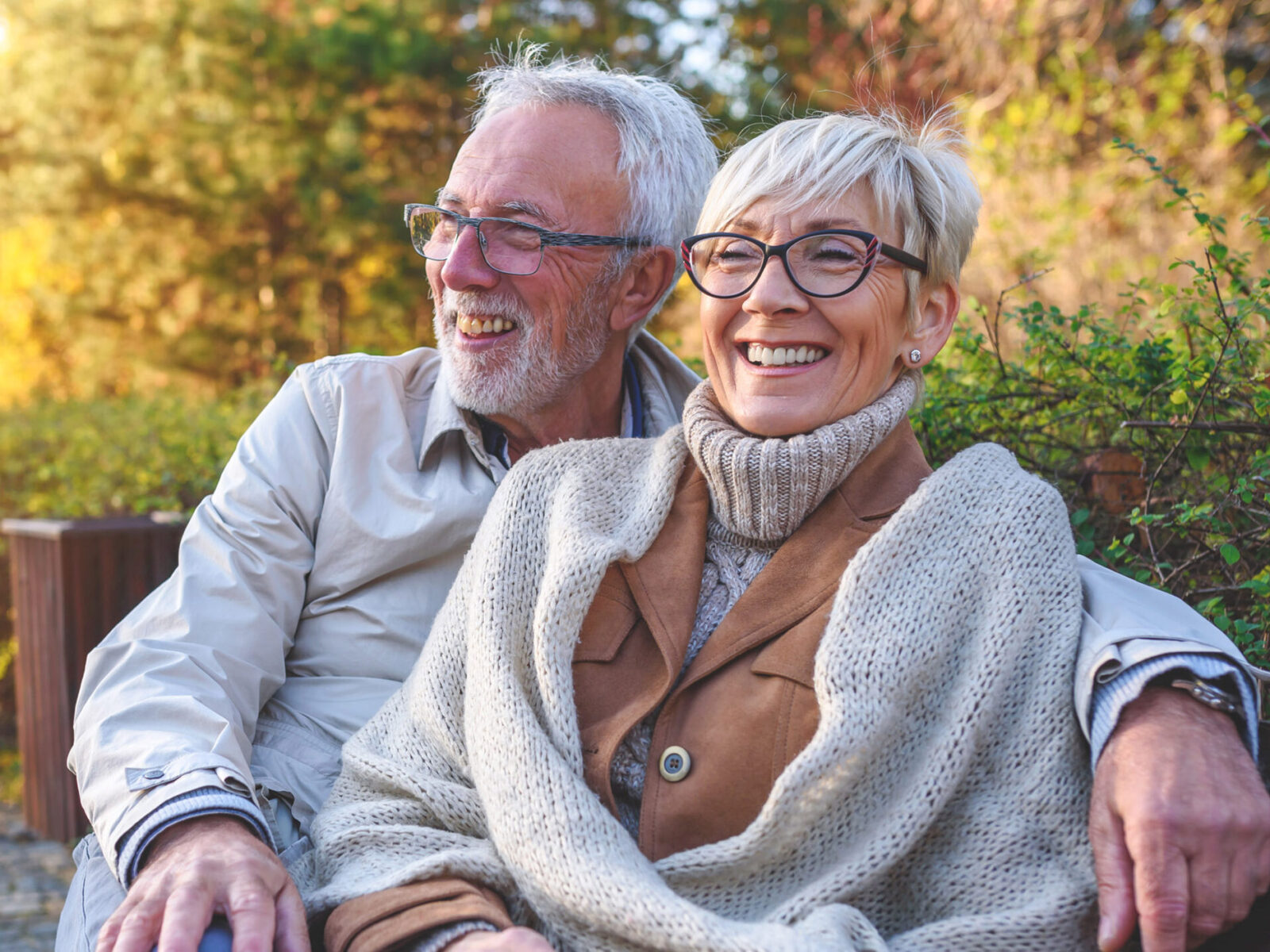 Smiling senior couple sitting on the bench in the park together