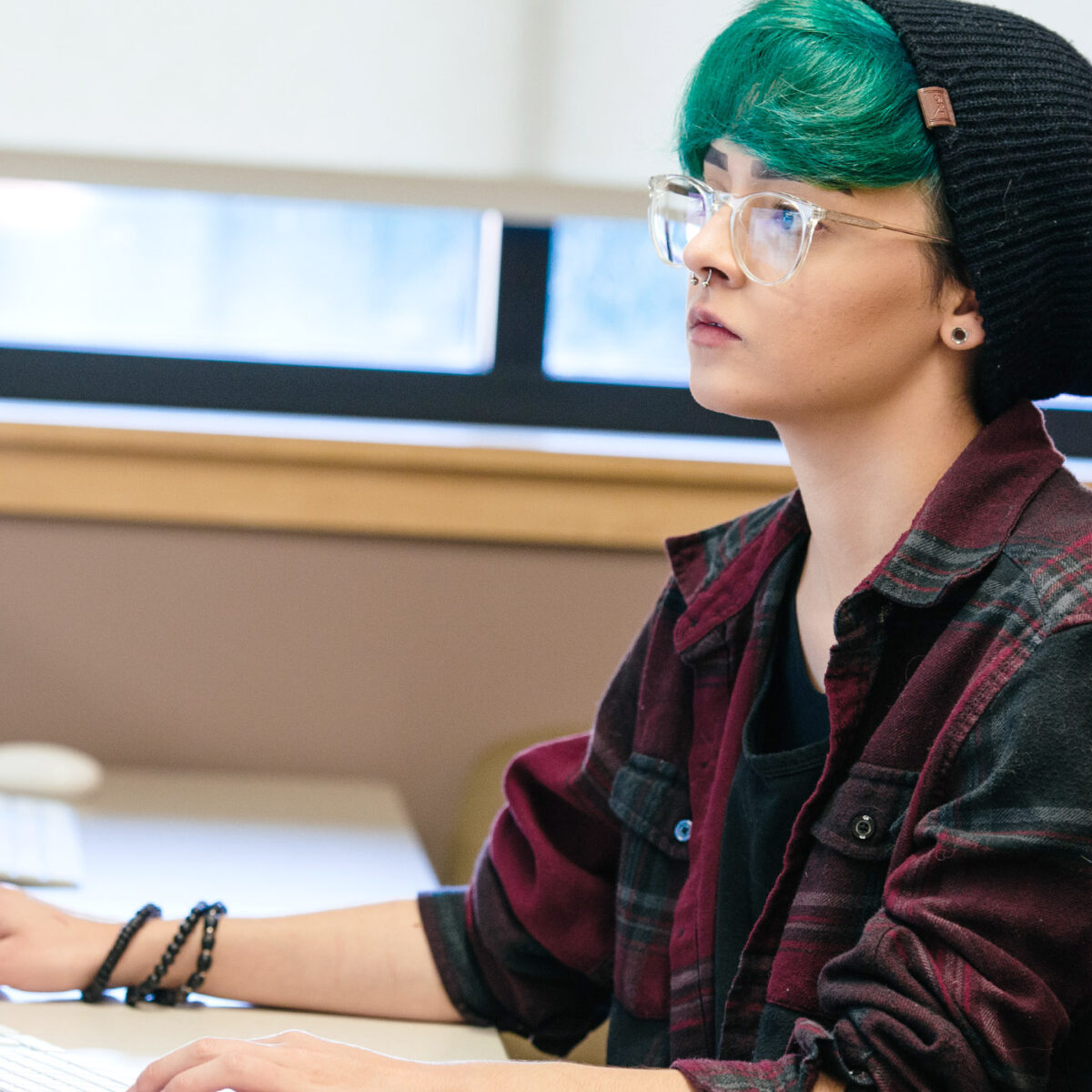 a student with colorful hair works intently at a computer