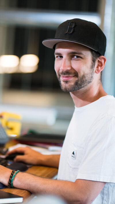 student working at a computer smiles at the camera