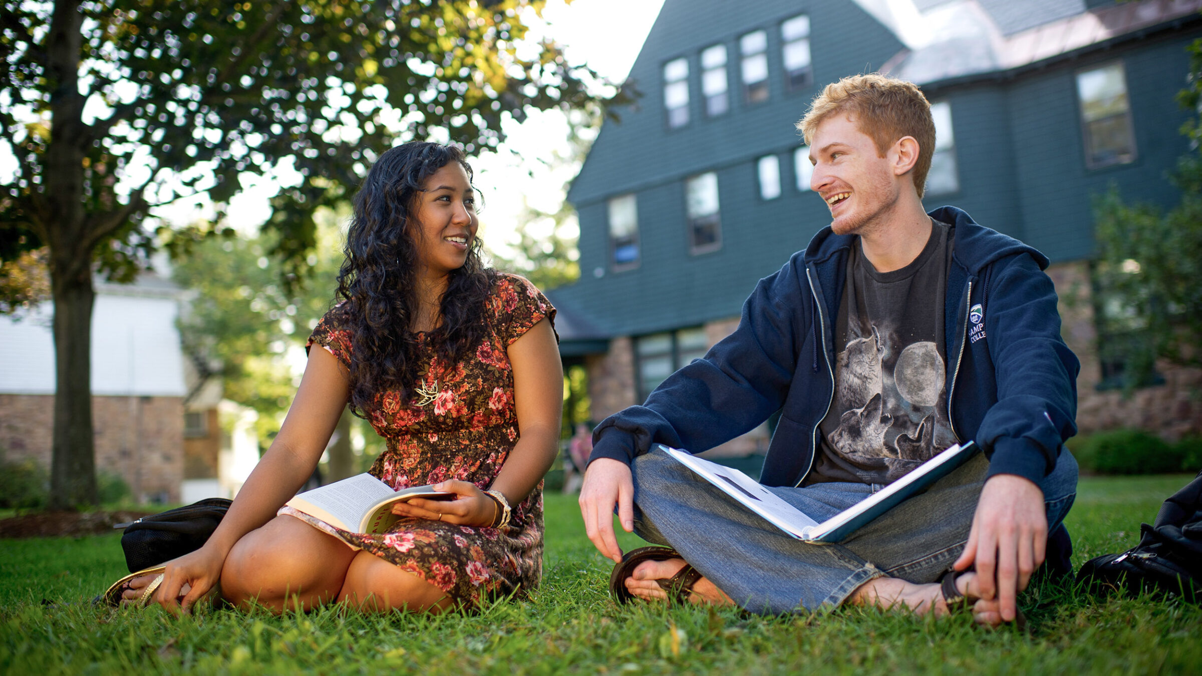 two students talk and study on the lawn