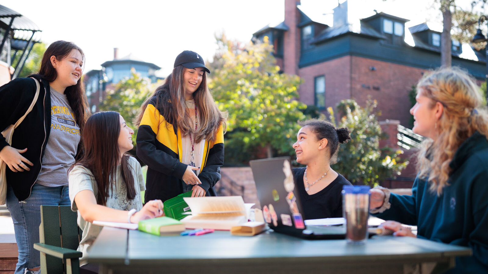 several students gather outside at a table with study materials