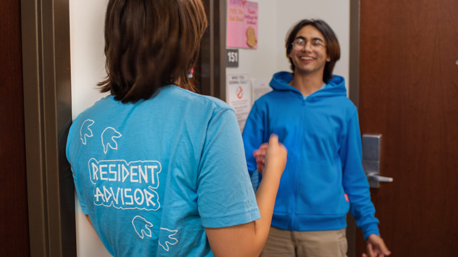 resident advisor talks with another student in hallway of res hall