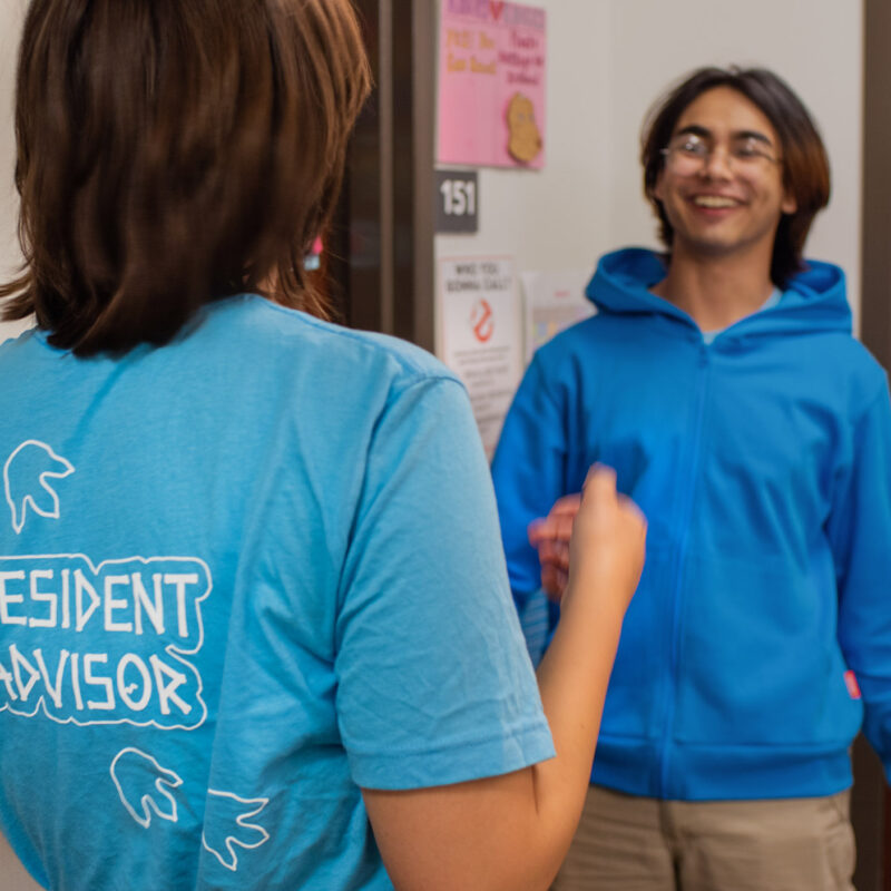 resident advisor talks with another student in hallway of res hall