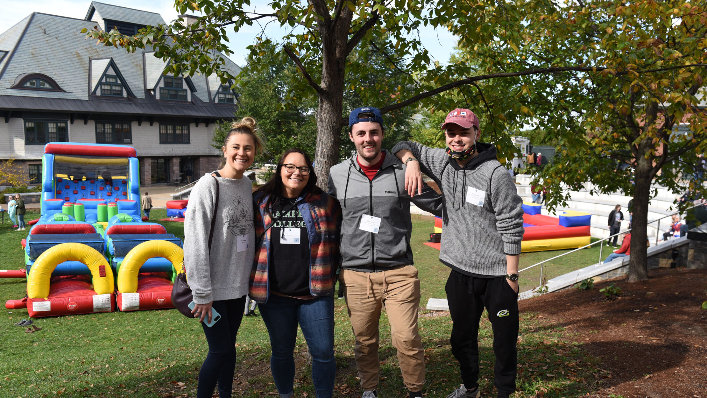 Four students stand together in front of an inflatable obstacle course on Champlain's campus