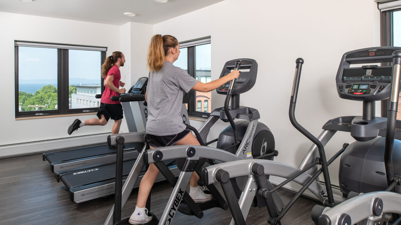 two students use the treadmill and elipticals in the 194 fitness room