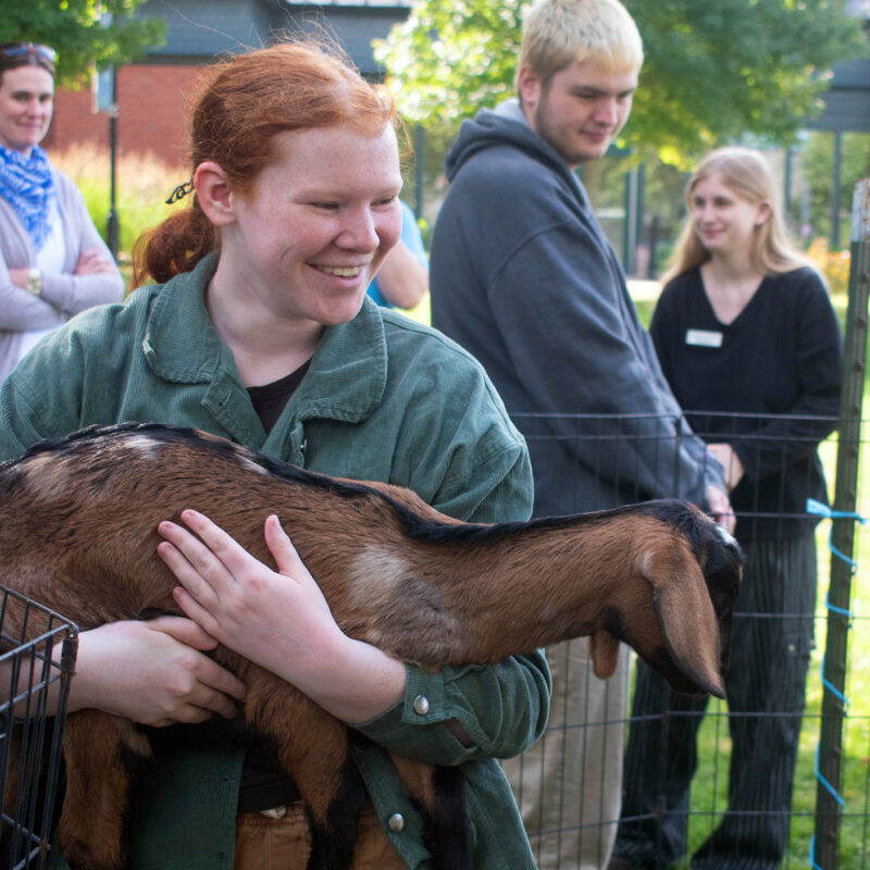 student holds a goat during a de-stress event