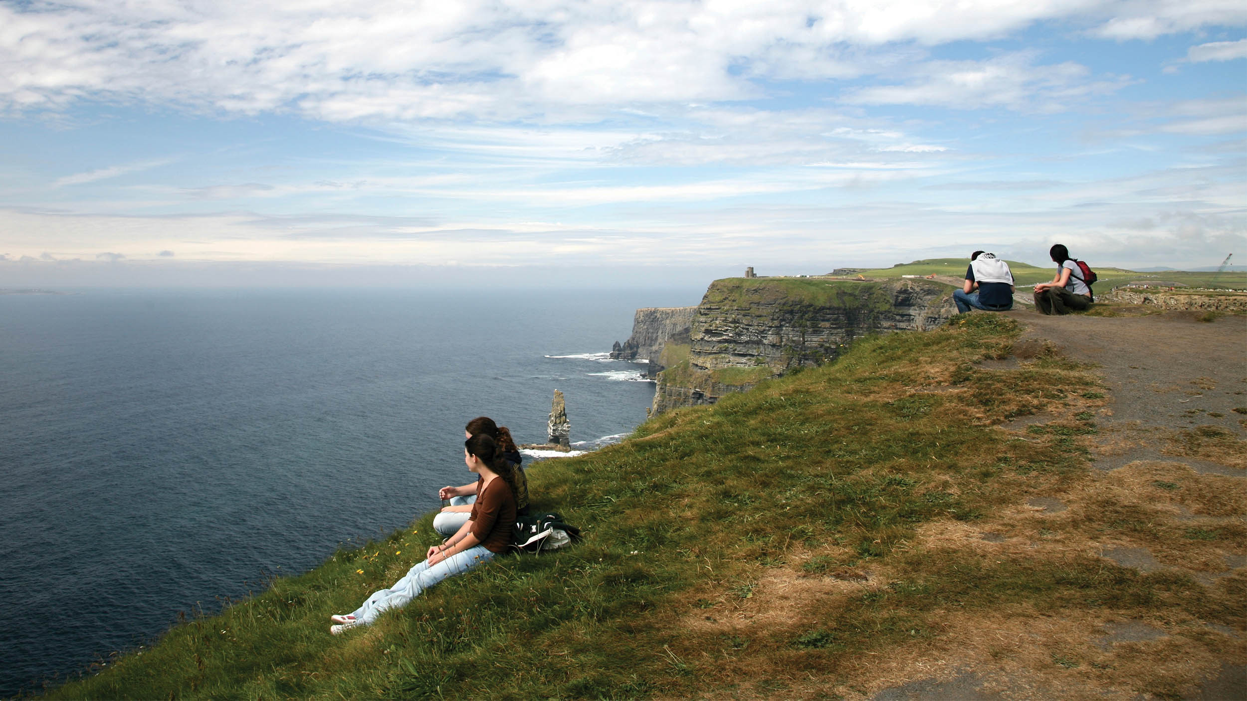 people sitting on a cliffside in Dublin Ireland looking over the ocean