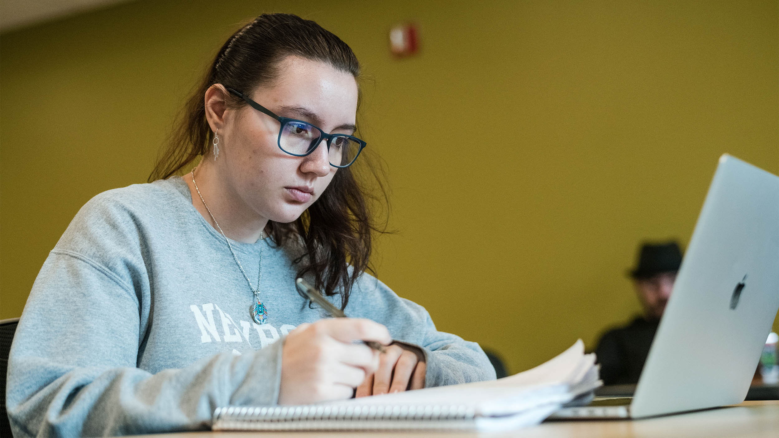 a student working on a laptop and writing in a notebook