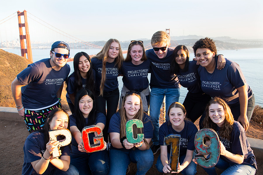 group poses for photo with the Golden Gate Bridge in background holding letters and numbers PGC19