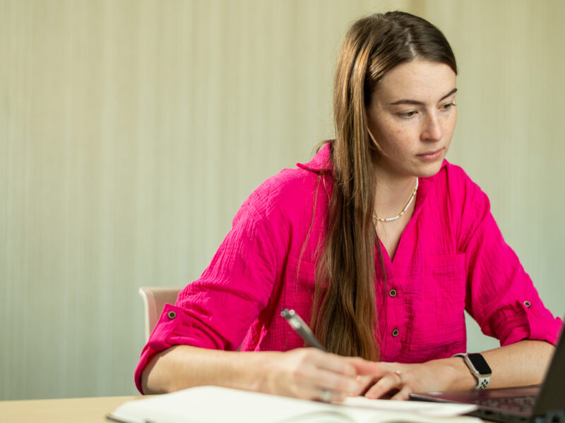 A student following along on a laptop while writing notes.