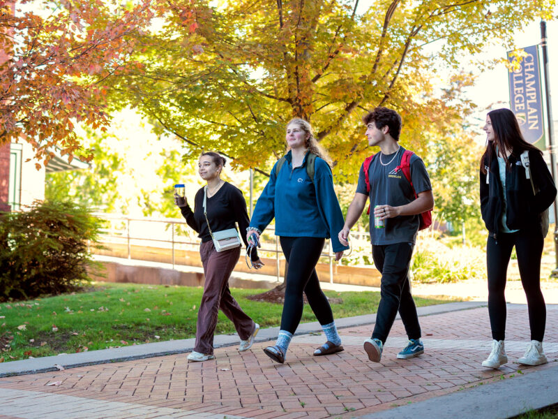 small group of students walk across campus on a sunny fall day