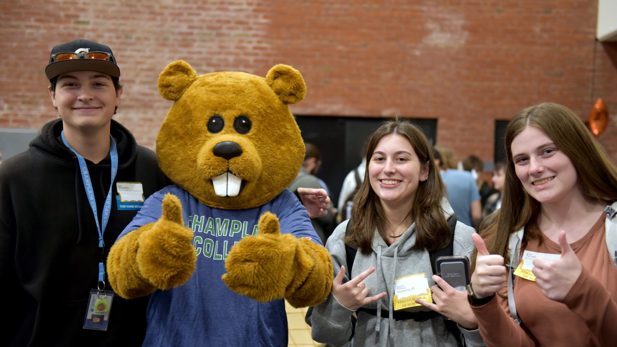Three students and Chauncy the Beaver Mascot giving thumbs up signs at a career fair.