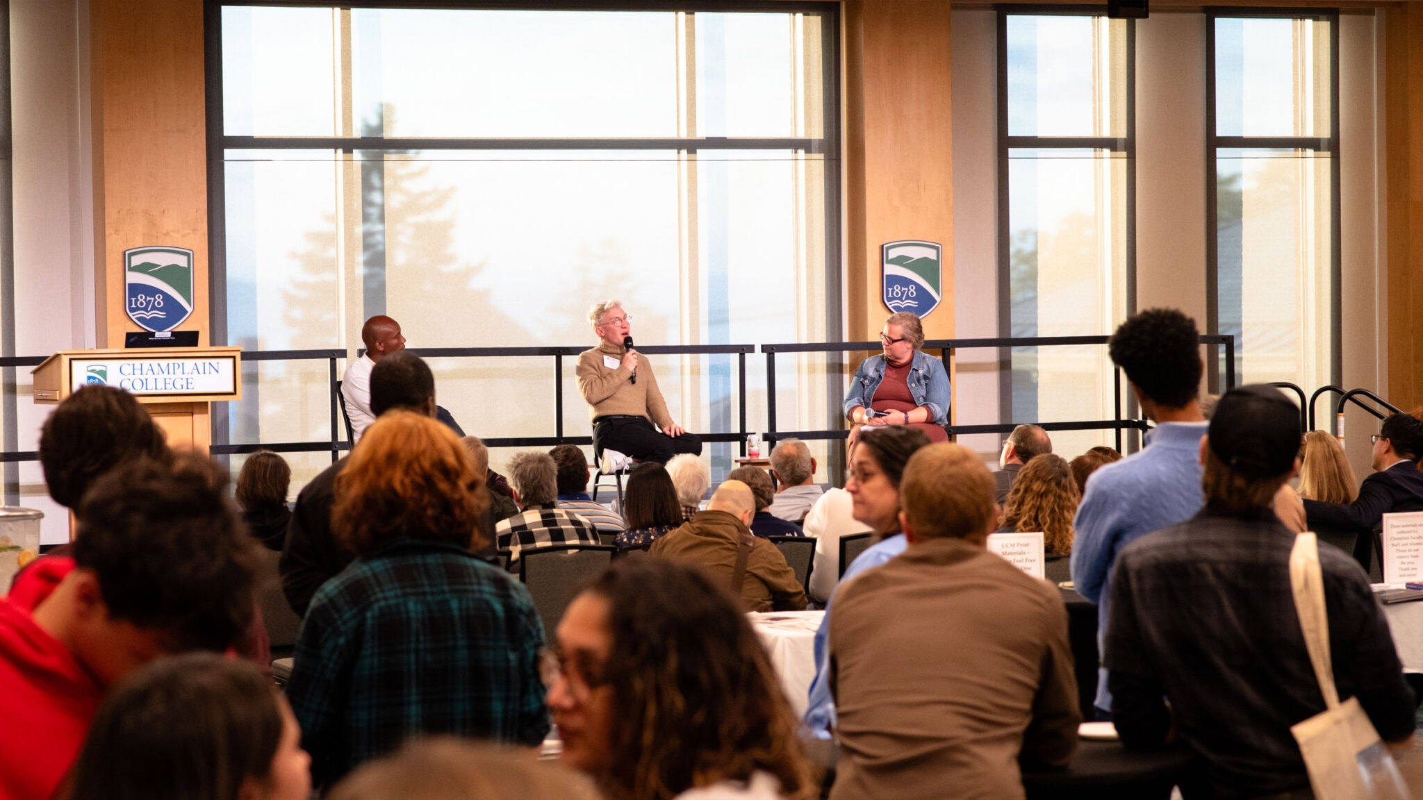 Two alumni and one professor from Champlain College sit on a stage in front of an audience to discuss digital storytelling, technology, and the future of humanities studies.