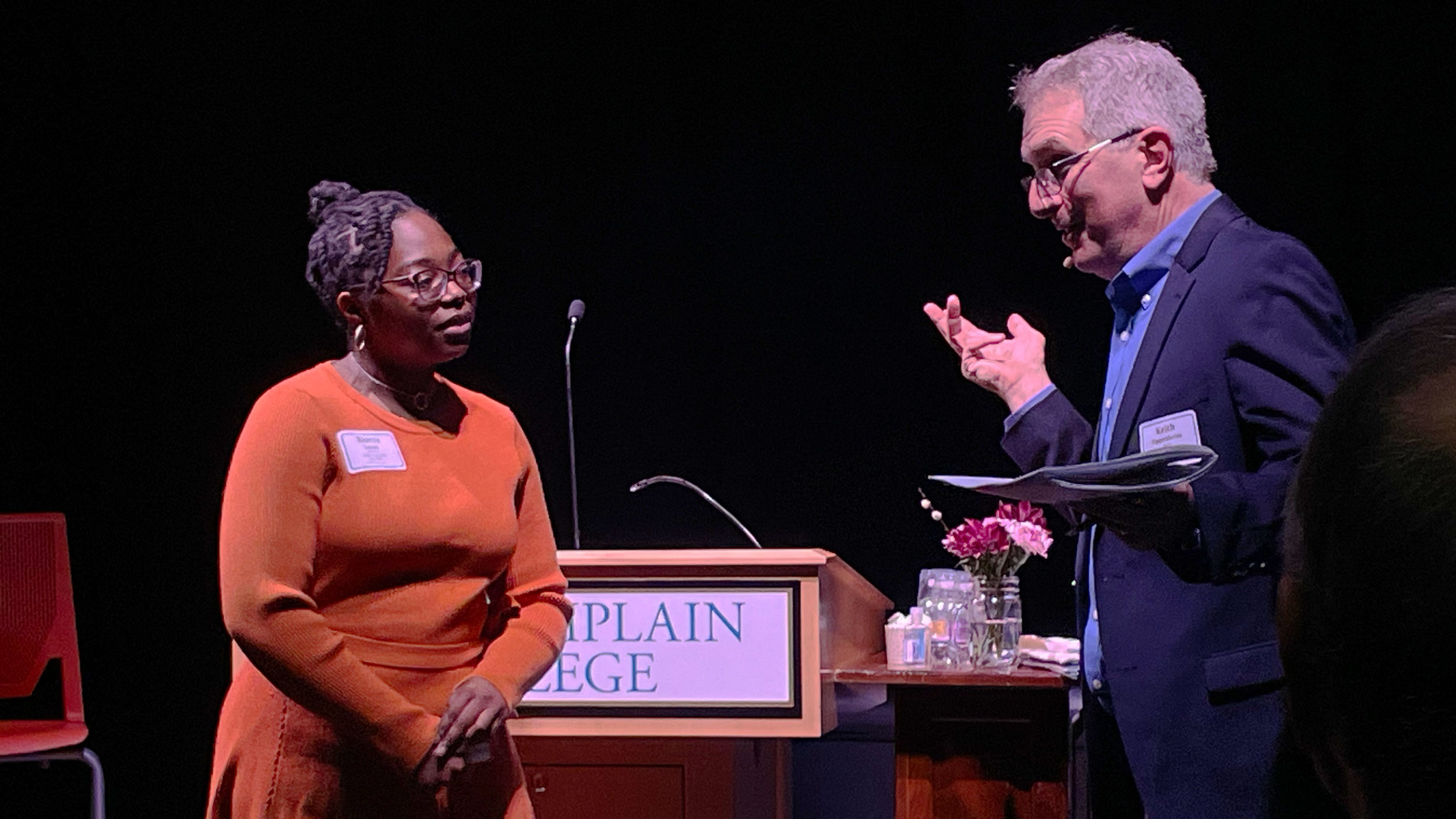 student and faculty member talking on stage