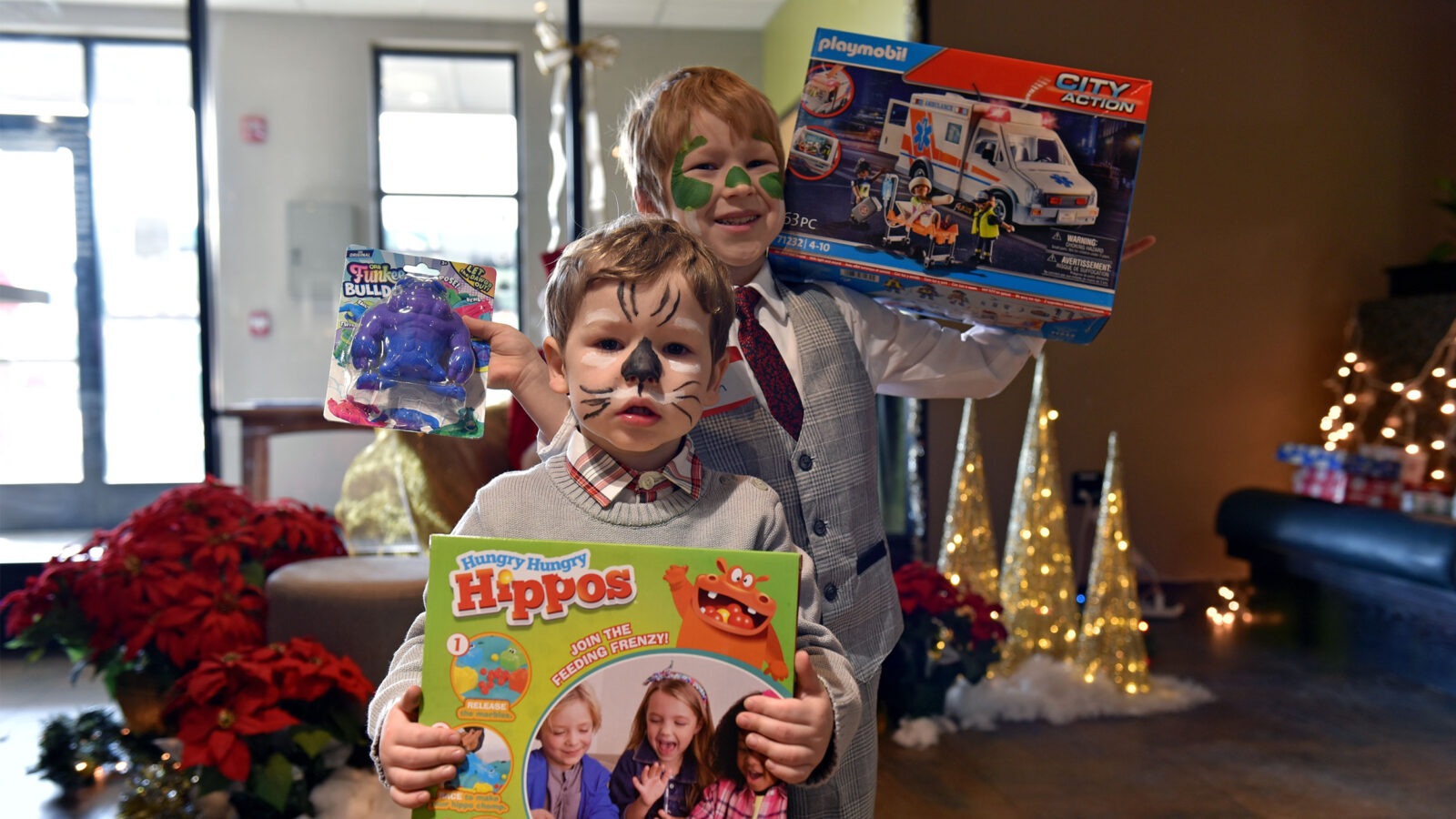 two kids hold up presents with their faces painted